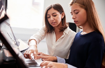 piano teacher and student 
sitting at a piano